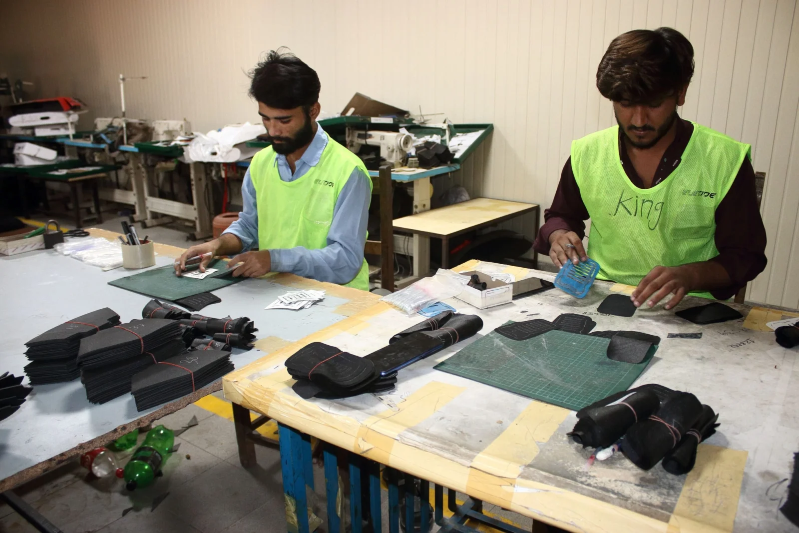 Workers preparing footwear components by hand