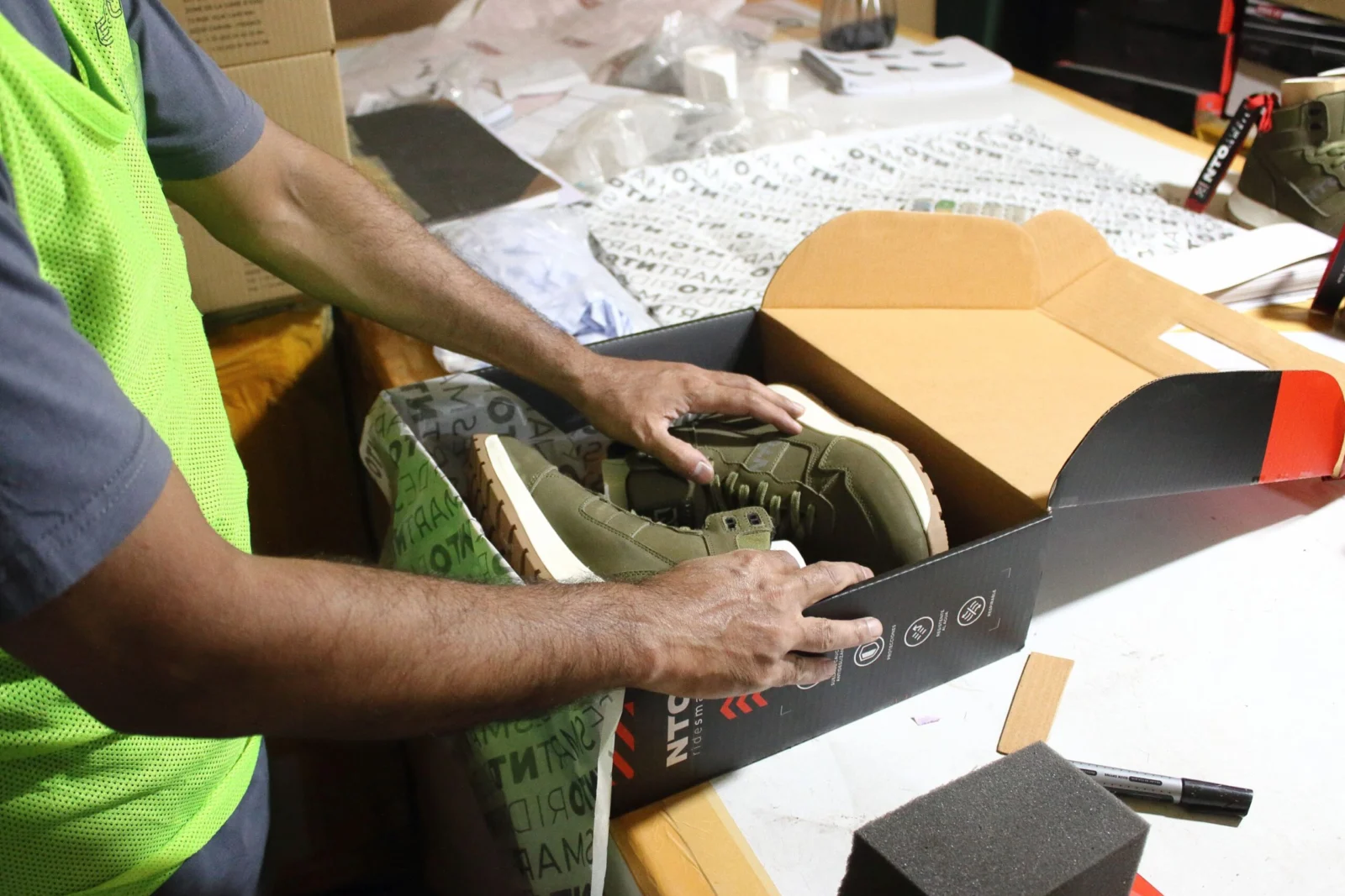 Worker packing motorcycle boots into a product box