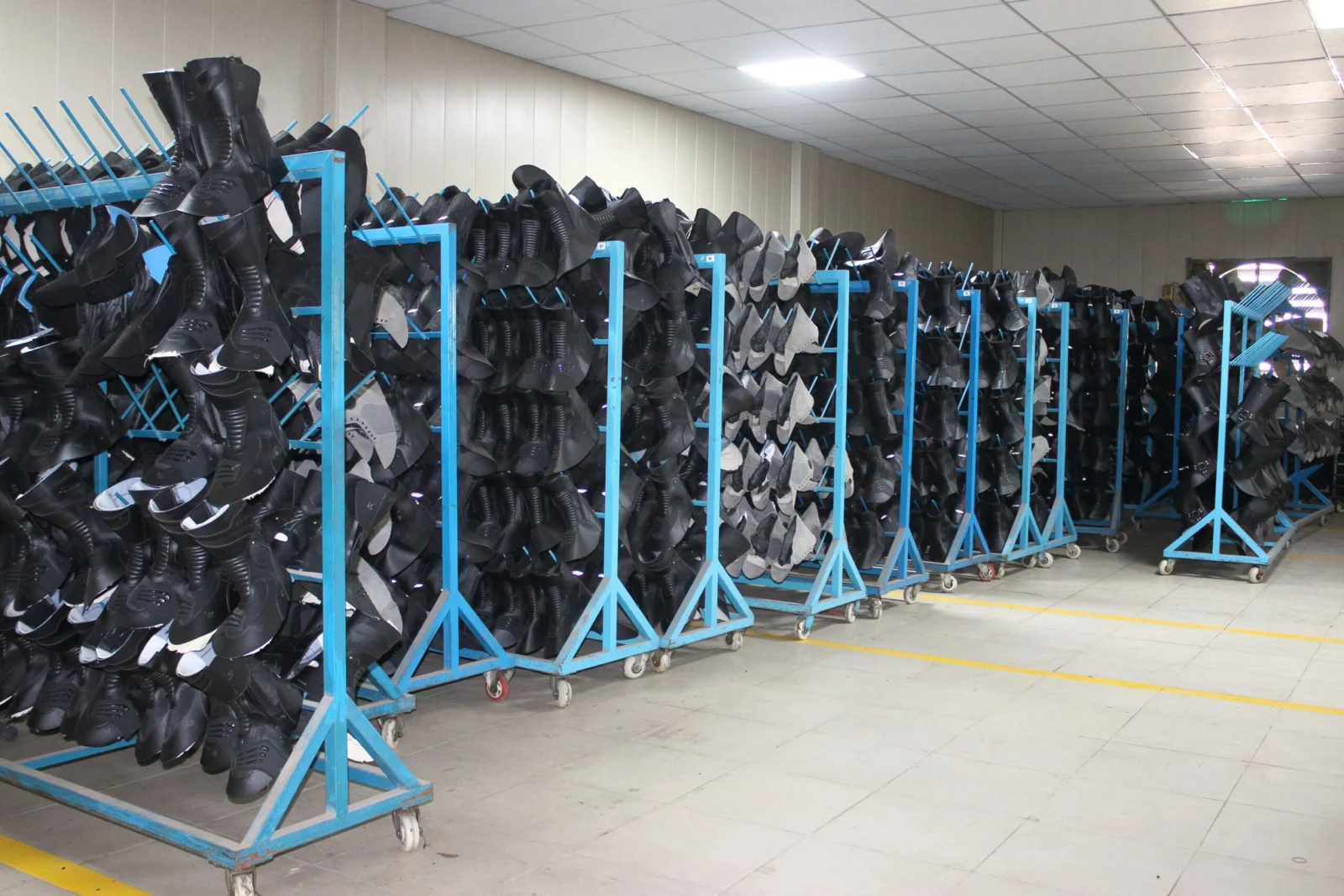 Motorcycle gear components: black boot uppers on blue production racks