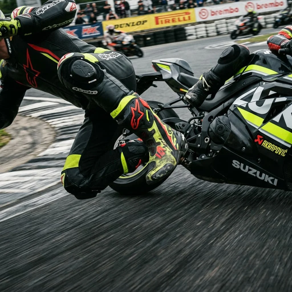 Motorcycle racer leaning into a corner on a race circuit — motorcycle gear manufacturer